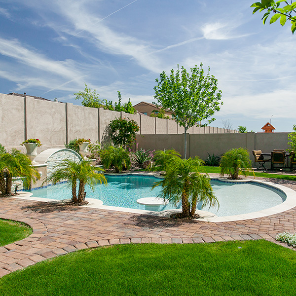 Pool with tables surrounded by green lush palm trees and flowers